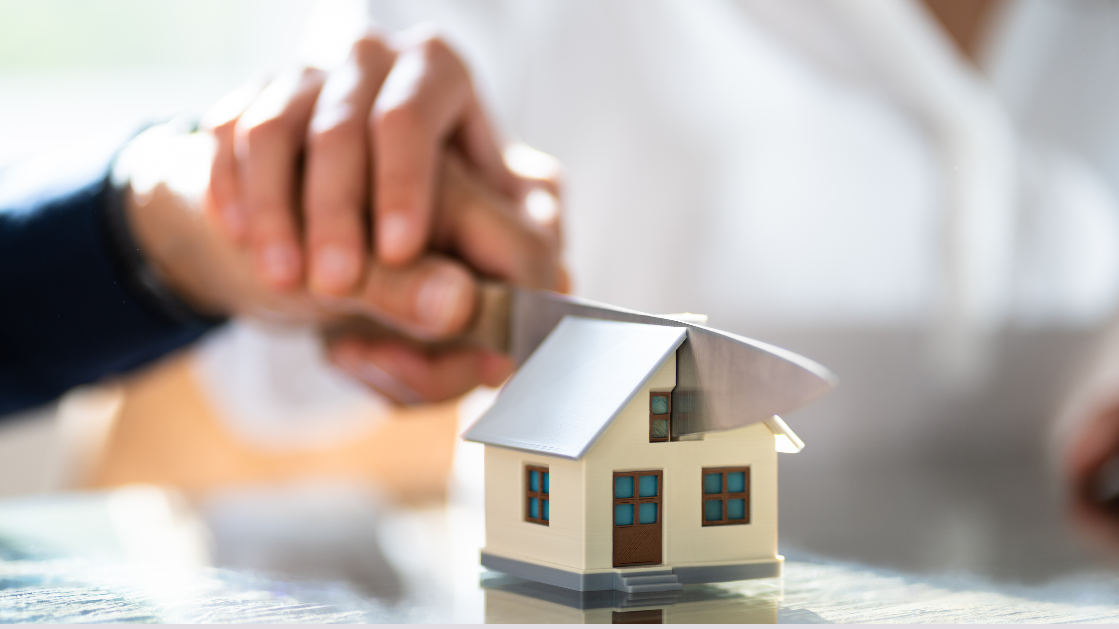 Two people cutting a house down the middle with a knife to symbolize splitting property