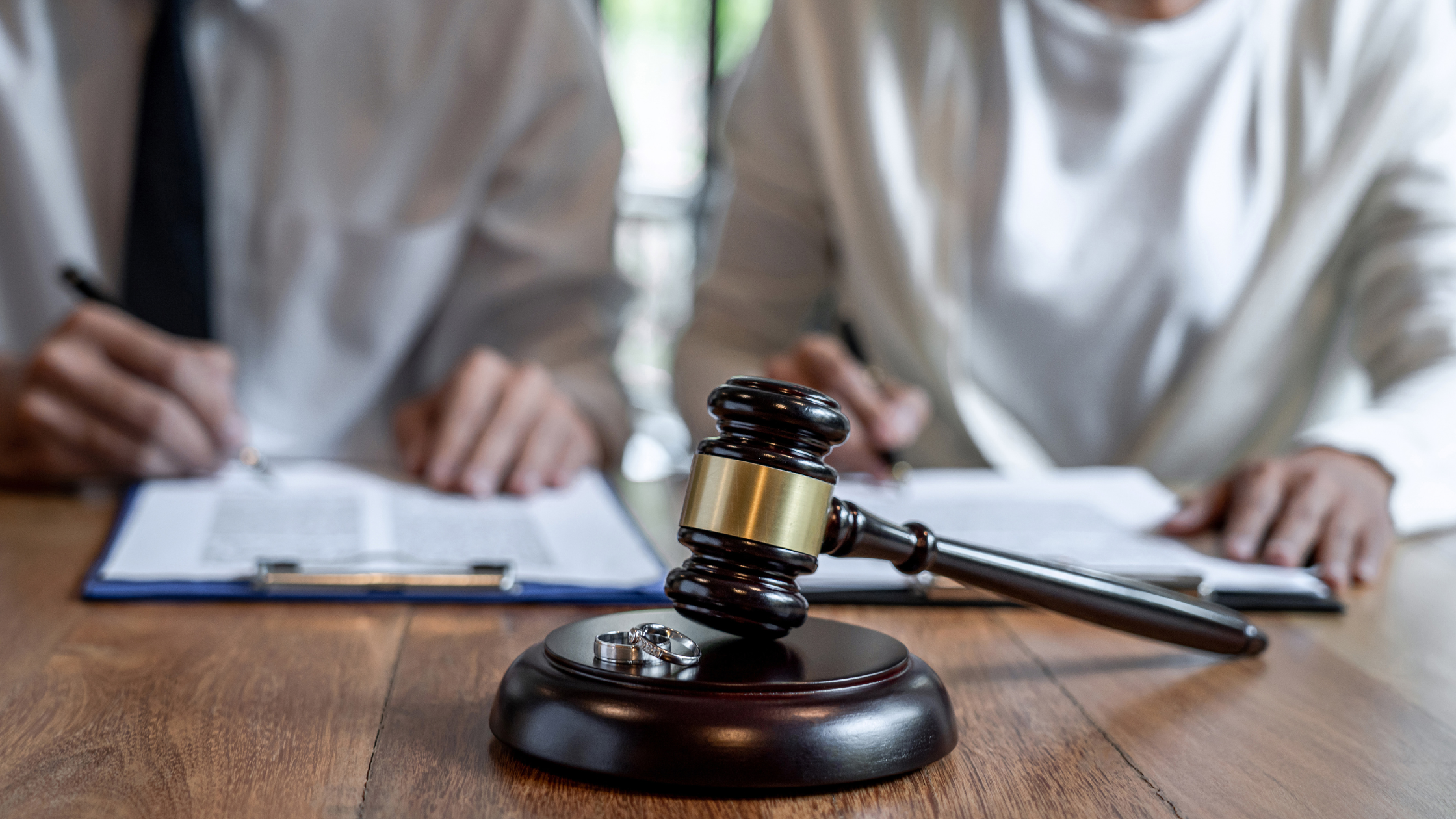 Couple signing divorce documents behind a gavel