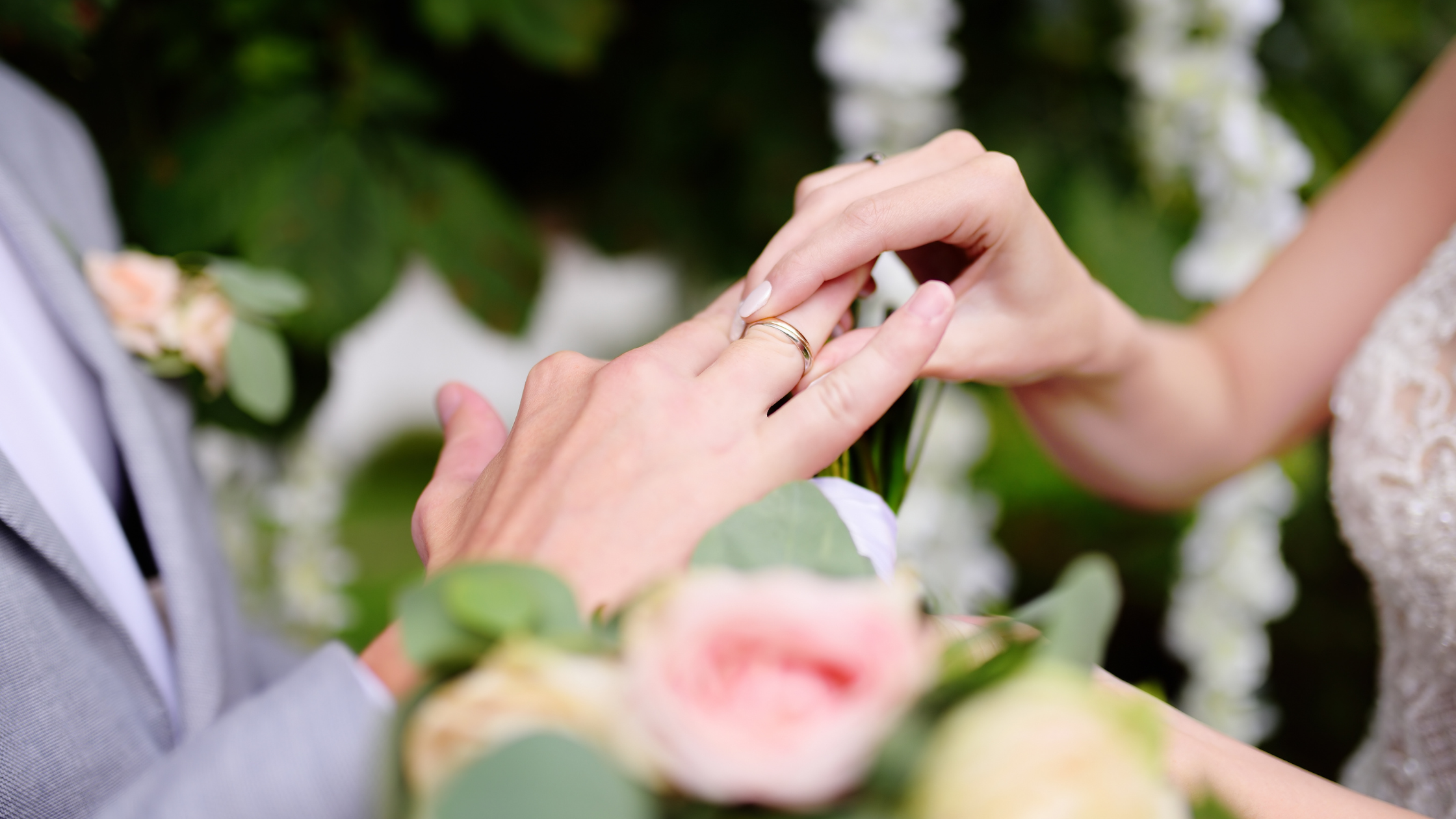 Wife putting ring on husbands finger during wedding