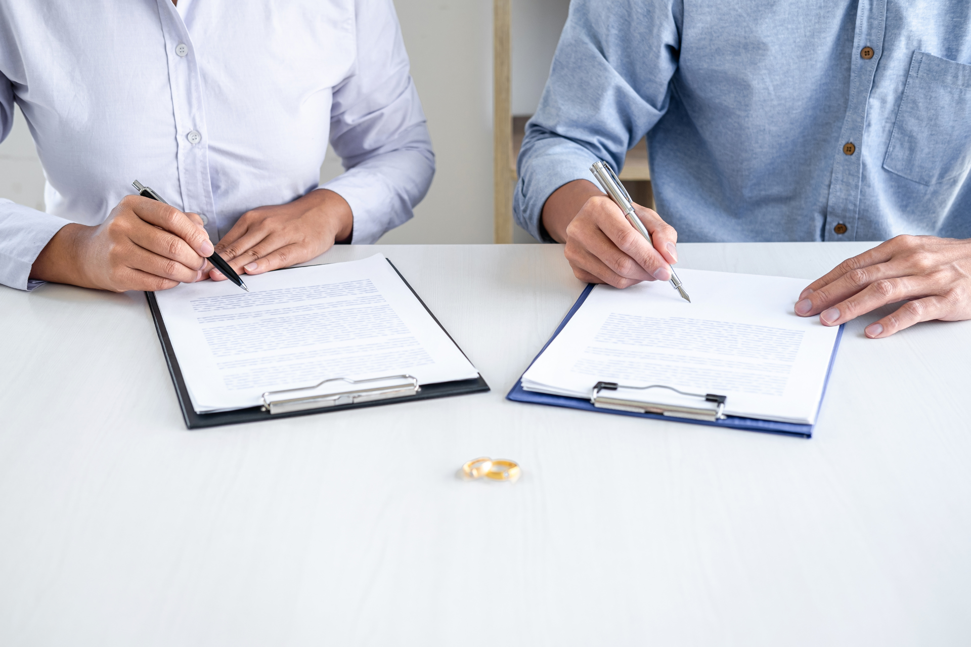 Man and woman sitting down, signing papers for a divorce