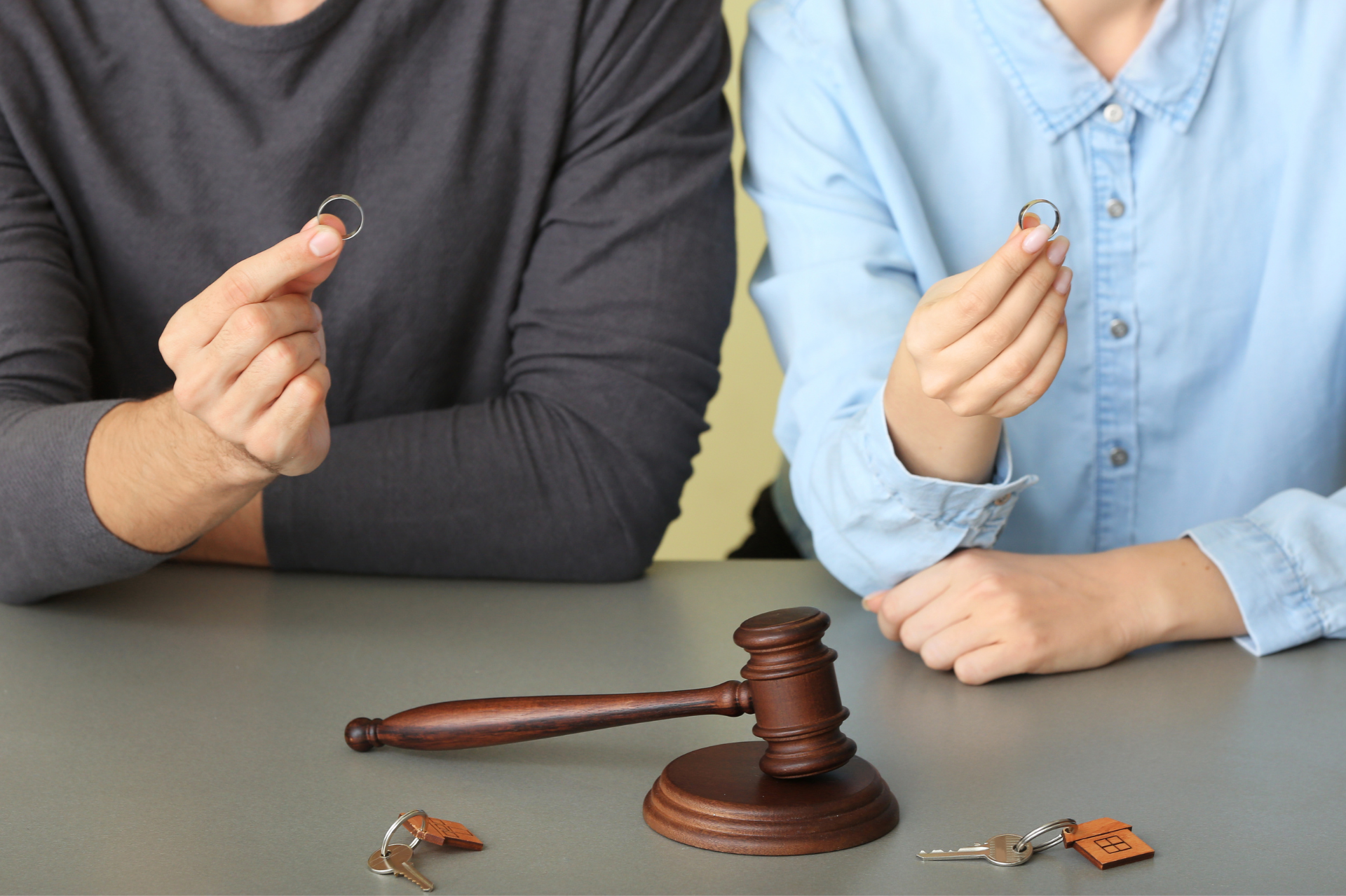 Couple holding their marriage rings in their hand with their home keys on the table ready for divorce 